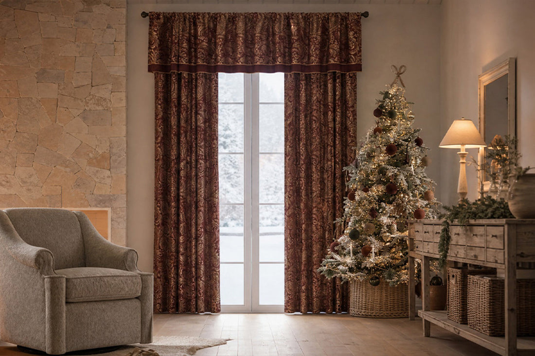 Madison Park Aubrey jacquard curtain panels in burgundy and gold with matching valance, framing a snowy window in a cozy living room with a lit fireplace, upholstered chair, and decorated Christmas tree.